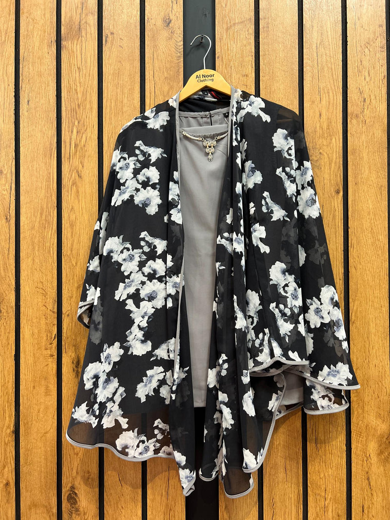 Floral kimono-style jacket with black and white pattern hanging on wooden background