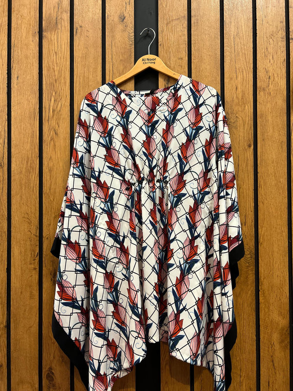 Stylish women's printed kimono with red and blue leaf patterns hanging on a wooden hanger against a wooden background